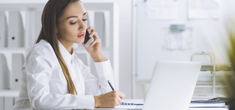 woman taking notes during a phone call